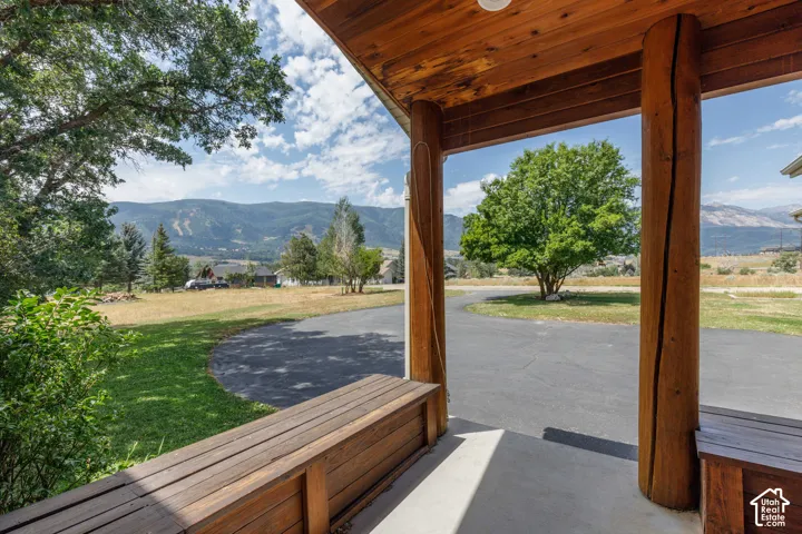 Covered porch featuring natural wood posts, wood-finish ceiling, and built-in wood benches