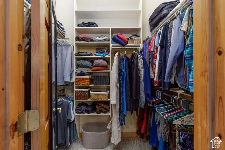 Spacious closet featuring built-in shelving, multiple hanging rods, and wood-finish doors
