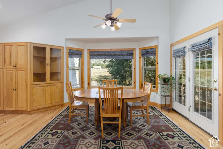 Vaulted ceiling with a ceiling fan, bay windows with wood trim, wood-finish flooring, built-in wood cabinetry with glass fronts, and double doors with vertical window panes