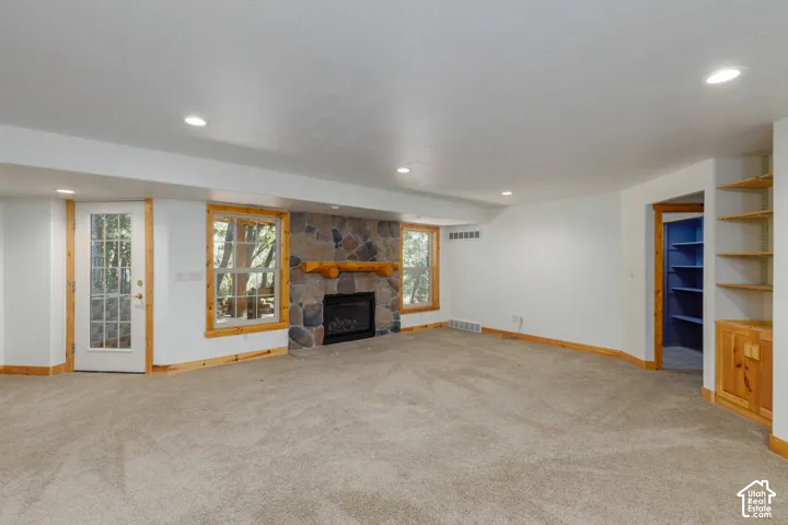 Stone-clad fireplace with wood mantel, built-in shelving, recessed lighting, and a glass-paneled door