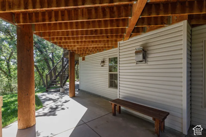 Covered concrete patio with exposed wood beam ceiling, wood support columns, and horizontal siding