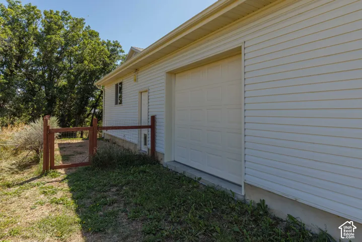 Attached garage with paneled door, horizontal siding, and perimeter fencing