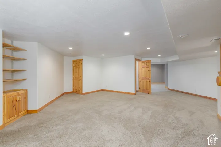 Recessed lighting, wood-finish trim, built-in shelving, wood-finish cabinetry, and neutral carpeting