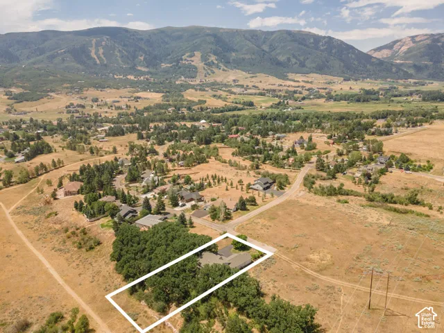 Expansive property featuring a residence surrounded by mature trees, set against a backdrop of rolling hills and distant mountains