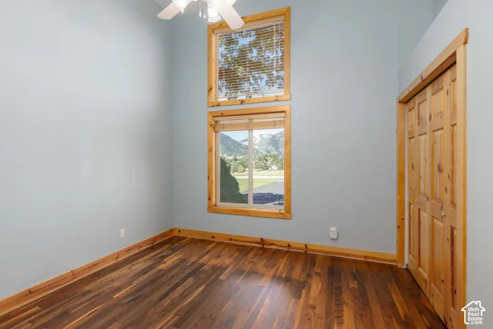 Wood-finish flooring with coordinating wood trim, a built-in ceiling fan, and a light-toned wall finish