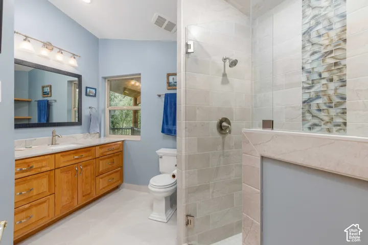 Bathroom featuring a spacious walk-in shower with light gray subway tile, a decorative glass tile accent strip, and a frameless glass enclosure