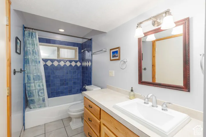 Bathroom featuring a white vanity with wood-finish cabinetry, a drop-in sink, and a framed mirror with an overhead light fixture