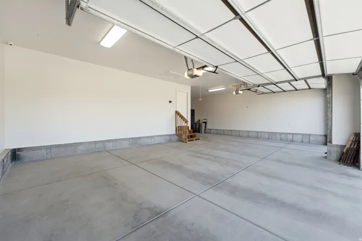 Expansive garage with concrete flooring, automatic garage door openers, and a built-in wooden staircase