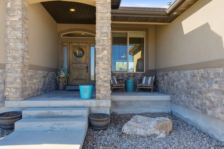 Stone veneer accents, stucco exterior, covered entry, wood-finish entry door, and concrete steps
