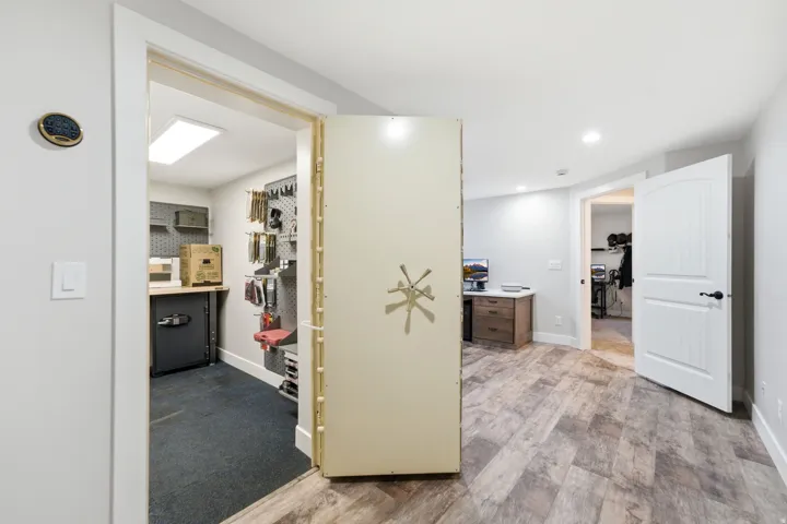 Vault / Gun Storage -Secure room with a heavy-duty vault door, wood-finish flooring, recessed lighting, and white paneled doors