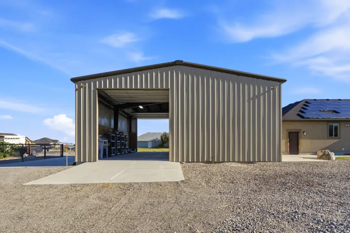 Metal car port with concrete slab and gravel ground cover
