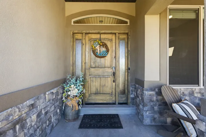 Entryway featuring a wood-panel door with frosted glass sidelights, a transom window, and stone veneer accents