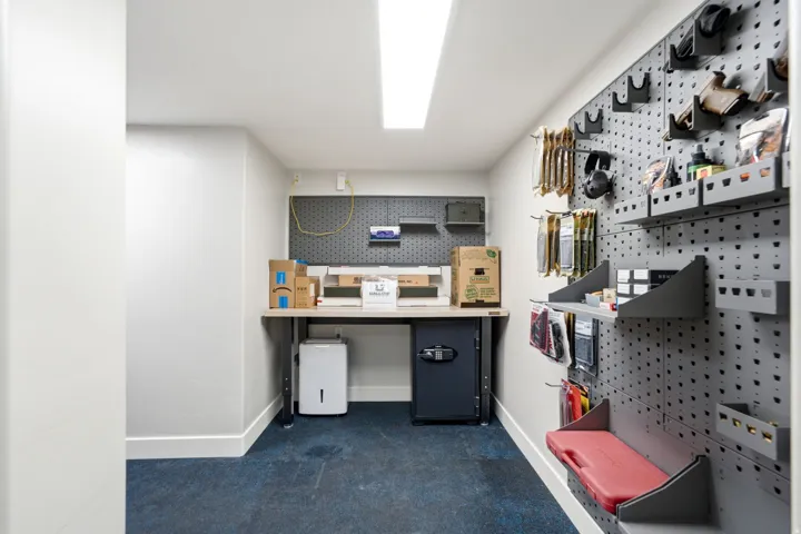 Vault / Gun Storage -Dedicated workspace featuring a built-in workbench, extensive pegboard storage, and integrated shelving