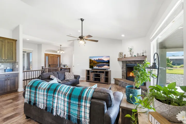 Vaulted ceilings, wood-finish flooring, and a stone-clad fireplace with a wood mantle