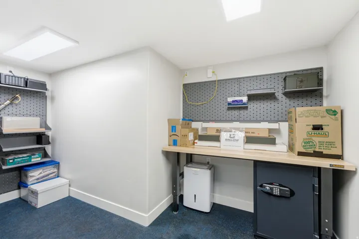 Vault / Gun Storage - Recessed ceiling lighting, full wall pegboard, built-in shelving, and light wood-finish workbench