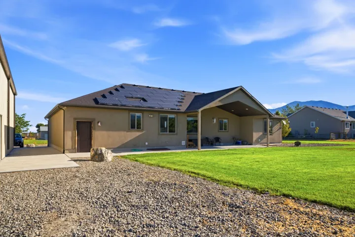 Stucco exterior with a covered patio, solar panels, and a concrete driveway
