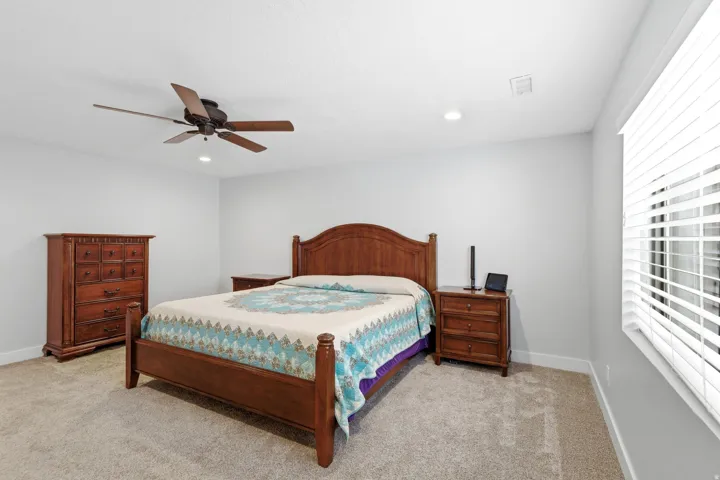 Recessed lighting, ceiling fan with wood-finish blades, and carpeted flooring