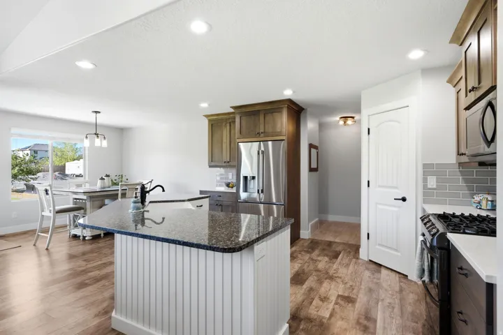 Kitchen featuring a central island with a dark countertop, stainless steel appliances, wood-finish flooring, recessed lighting, and light-toned cabinetry