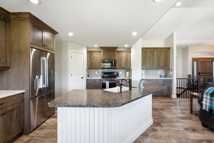 Kitchen featuring a large island with granite countertop, built-in sink, and white beadboard paneling