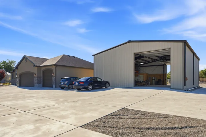 Expansive paved driveway and a detached metal-sided outbuilding with a large roll-up door