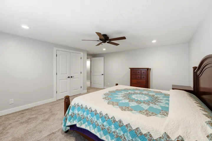 Recessed ceiling lighting, ceiling fan, white paneled doors, light gray wall finish, and carpeted flooring
