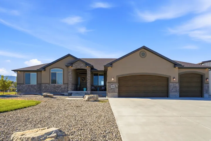 Stucco and stone facade with an arched entry, multiple large windows, and a three-car garage