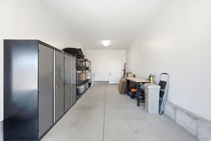 Concrete flooring in a spacious garage with a white entry door