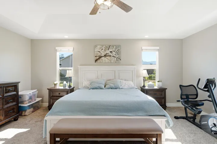 Tray ceiling with a ceiling fan, recessed lighting, and soft neutral wall tones