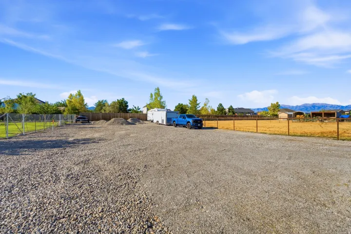 Expansive gravel lot with perimeter fencing and distant mountain scenery