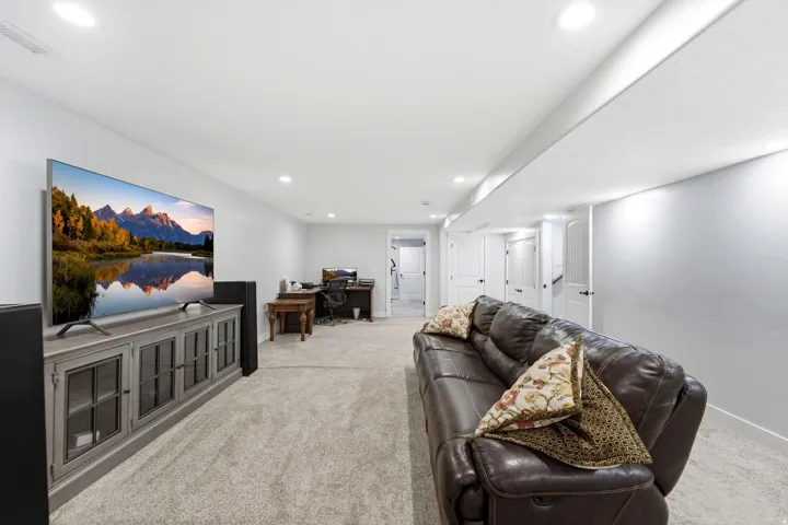 Recessed lighting illuminates a spacious room featuring light gray carpeting