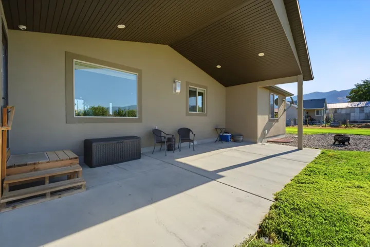 Expansive concrete patio with a covered section, recessed lighting, and stucco exterior