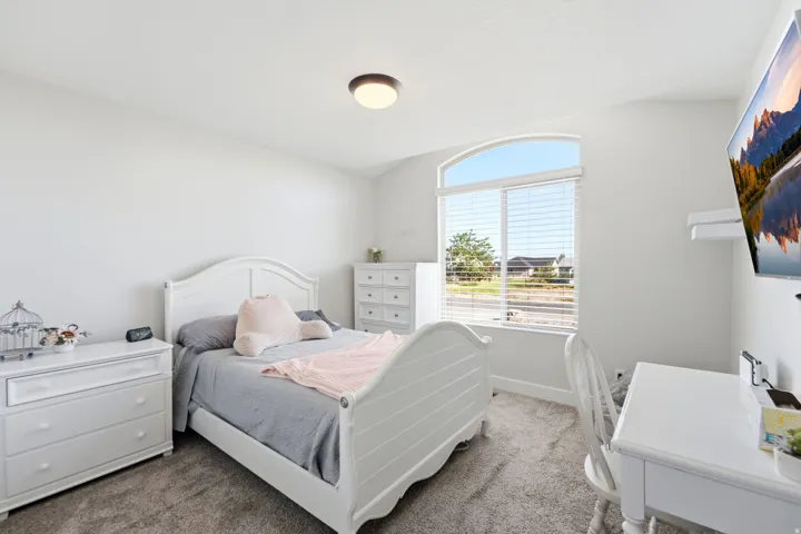 Arched window with blinds, wall-mounted television, and flush-mount ceiling light