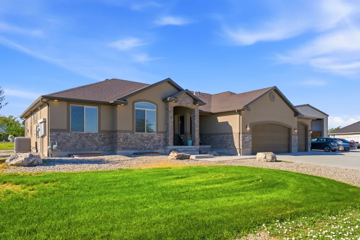 Stucco exterior featuring stone detailing, arched entry, and a two-car garage