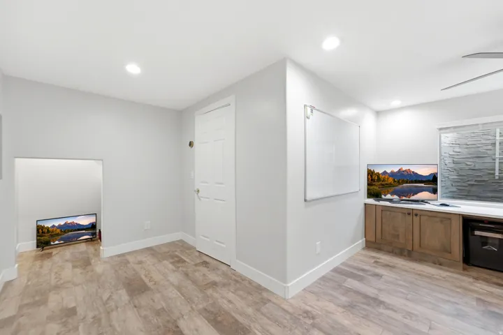 Wood-finish flooring, recessed lighting, white trim, built-in cabinetry, and a window with horizontal blinds