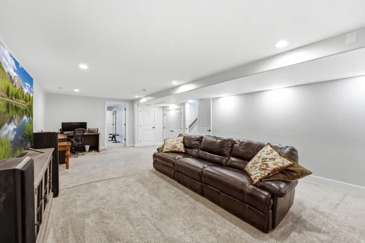 Recessed lighting illuminates the carpeted flooring and light gray walls