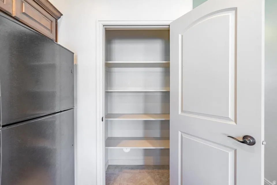 Bright pantry with multiple adjustable shelves and a classic white arched panel door