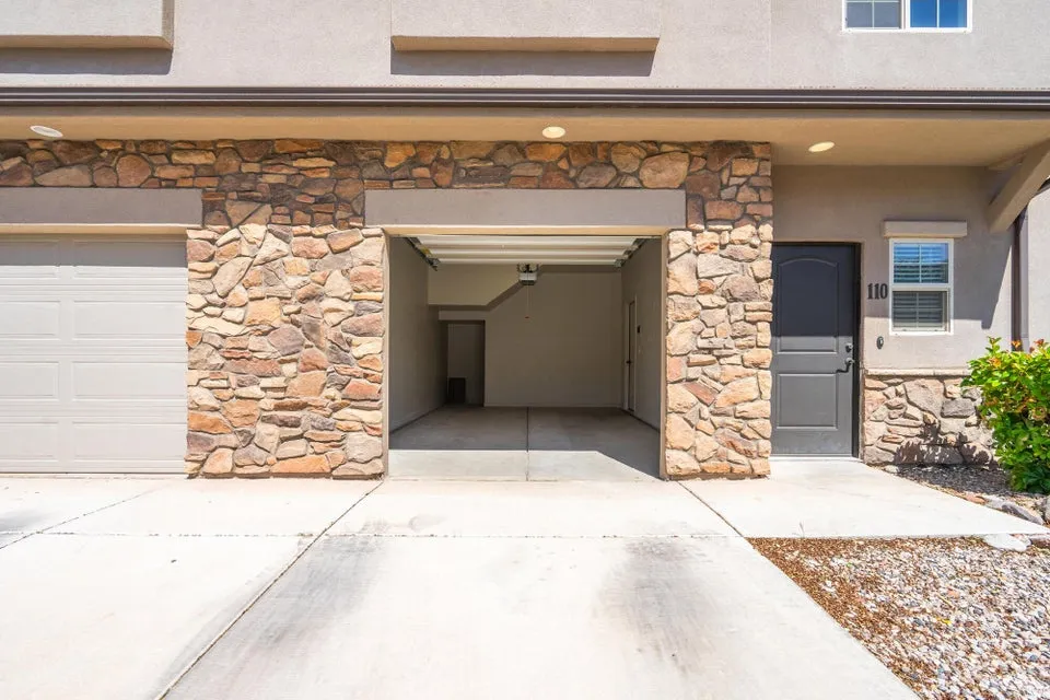 Stone veneer accents on the facade complement the light stucco exterior