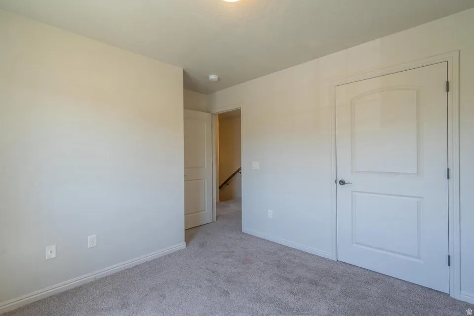Carpeted interior room featuring light-toned walls, white trim, and two white panel doors with brushed nickel hardware