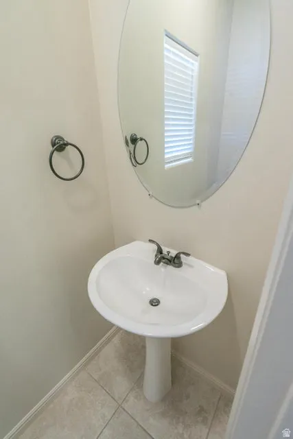 Pedestal sink with dual-handle faucet, set against light neutral walls and tile flooring