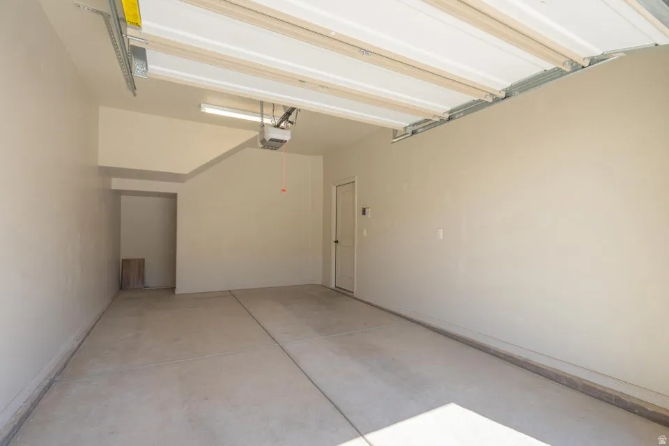 Spacious garage featuring concrete flooring, a white overhead door mechanism, and a side door for additional access