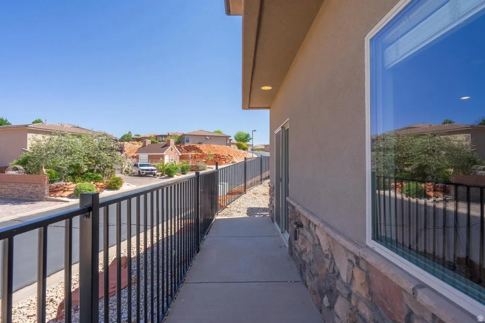 Exterior walkway featuring a stucco facade, stone veneer detailing, and a black wrought iron fence