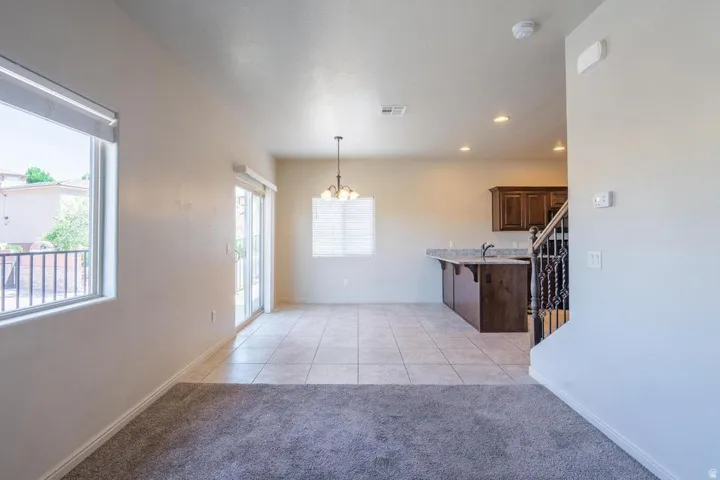 Open-concept living area featuring a kitchen with dark wood-finish cabinetry, a breakfast bar with a light-colored countertop, and a stainless steel sink