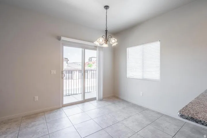 Light-filled room featuring large format tile flooring and a sliding glass door opening to a balcony with black metal railings