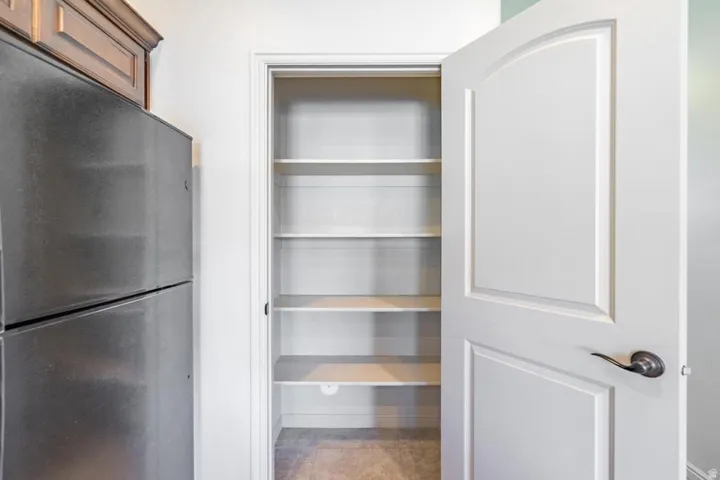 Bright pantry with multiple adjustable shelves and a classic white arched panel door
