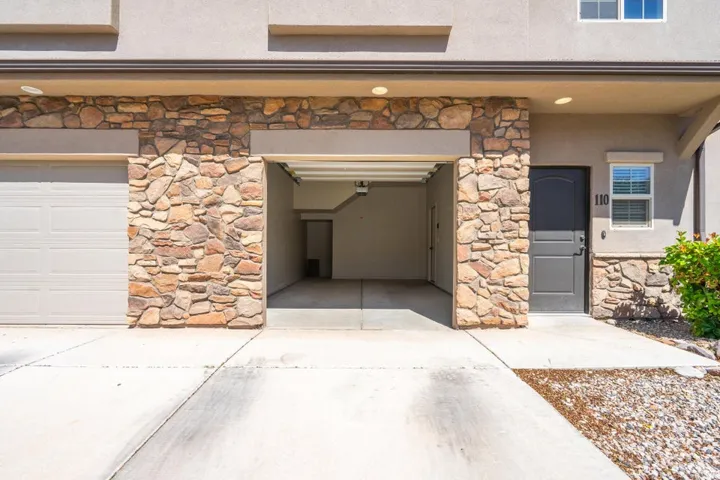 Stone veneer accents on the facade complement the light stucco exterior