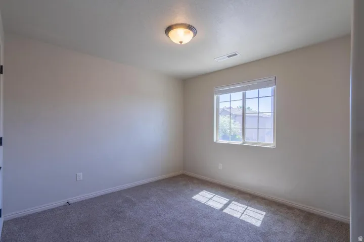 Carpeted room with neutral wall tones and a single window featuring blinds