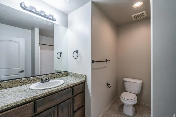 Bathroom featuring a wood-finish vanity with a light granite countertop, undermount sink, and dark bronze fixtures