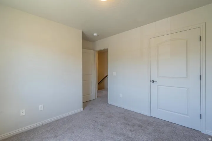 Carpeted interior room featuring light-toned walls, white trim, and two white panel doors with brushed nickel hardware