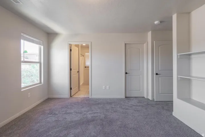 Carpeted room featuring a single window, built-in shelving, and multiple arched panel doors