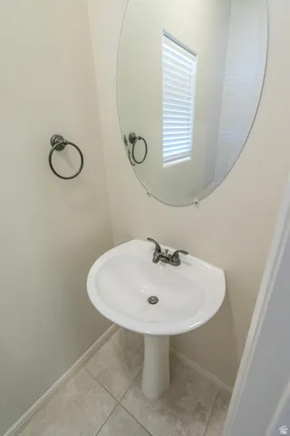Pedestal sink with dual-handle faucet, set against light neutral walls and tile flooring